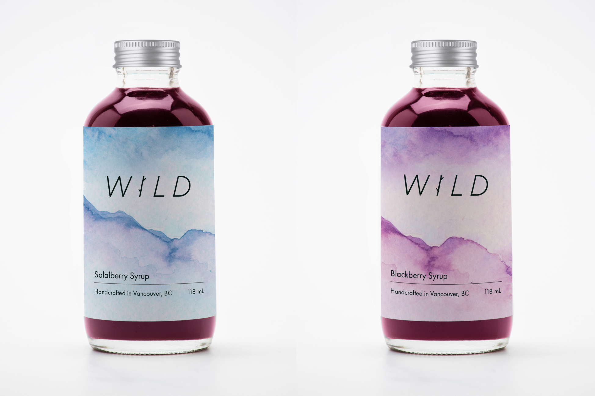 two bottle mockups of salalberry and blackberry syrups on a white background